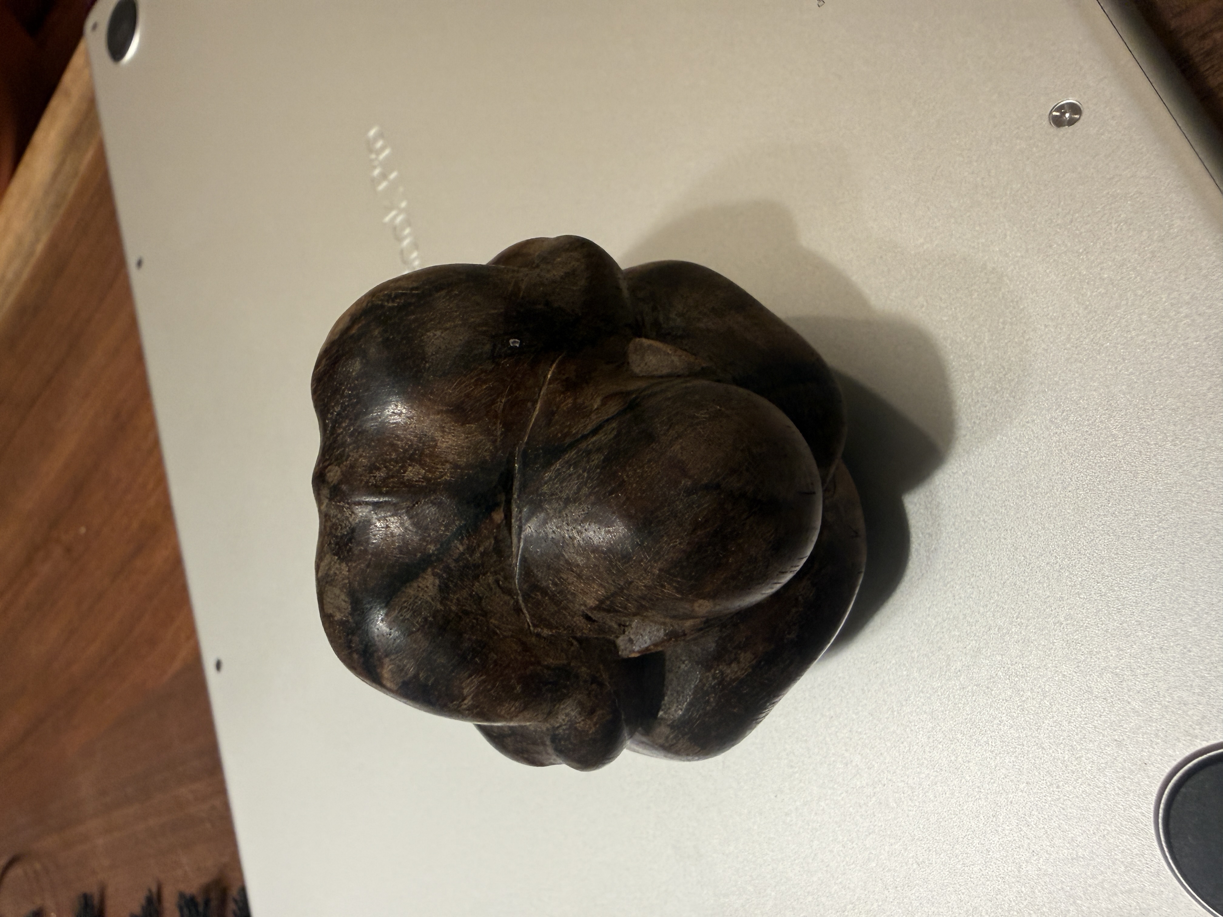 Top-down view of the same carved figure, showing the body curled so tightly it becomes almost spherical — pure form